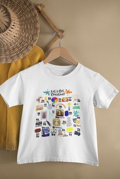 a white t - shirt hanging on a wall next to a straw hat and basket