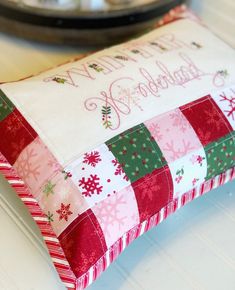 a close up of a pillow on a table with a plate in the back ground