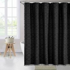 a bathroom with a black shower curtain next to a white bath tub and wooden stool