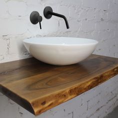 a white bowl sink sitting on top of a wooden counter next to a faucet