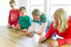 a group of people playing with rocks on a wooden table in front of a window