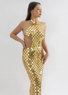 a woman wearing a gold sequin dress with cut out back and high slits