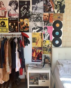 a bedroom with posters on the wall and various clothes hanging up in front of it