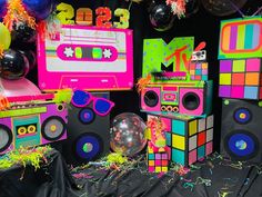 colorful party decorations including boomboxs, balloons and streamers on a black background