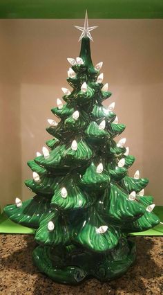 a green glass christmas tree with white lights