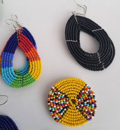 three pairs of beaded earrings are displayed on a white surface, one is multicolored and the other is black