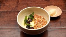 a white bowl filled with food on top of a wooden table