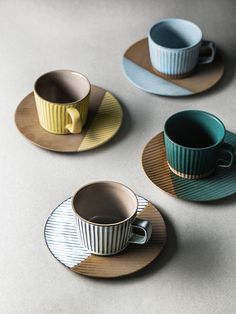 three cups and saucers are sitting on the table top, one has a yellow stripe