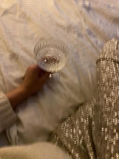 a person laying on a bed with a glass bowl in their hand and another persons leg