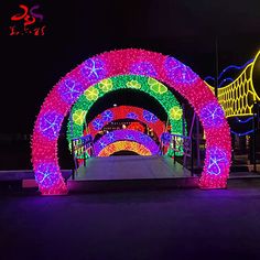 an archway covered in colorful lights at night