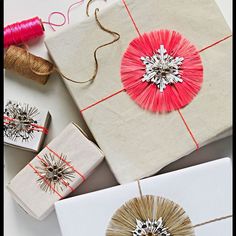 wrapped presents with red and white decorations on them, sitting next to twine spools