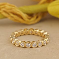 a yellow gold ring with five round diamonds on the side and a flower in the background