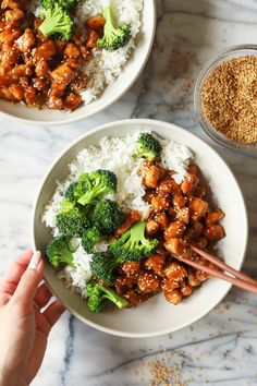 two bowls filled with rice, broccoli and chicken on top of a marble counter