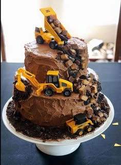 a three tiered chocolate cake with construction trucks on top