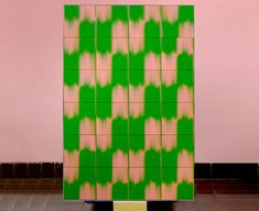 a large green and pink tile wall next to a tiled floor