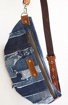 a purse made out of old jeans is hanging on a hook with a leather strap