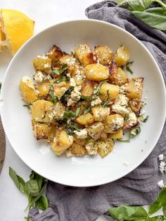 a white bowl filled with potato salad next to an orange and green leafy garnish