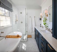 a bathroom with blue cabinets and a white bathtub next to a walk in shower