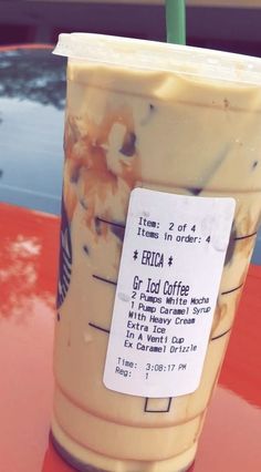 an iced coffee cup with a green straw in it sitting on a table next to a car