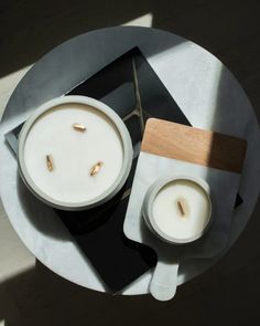 two white candles sitting on top of a black and white plate next to each other