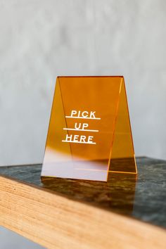 a glass trophy with the words pick up here on it sitting on top of a wooden table