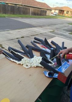 someone is making something out of fake toothbrushes on a table outside by the street