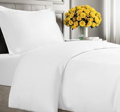 a bed with white sheets and yellow flowers