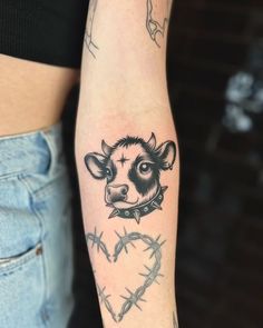 a woman's arm with a tattoo on it that has a cow head and barbed wire around it