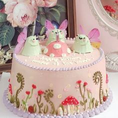 there is a cake decorated with pink flowers and two little bugs sitting on top of it