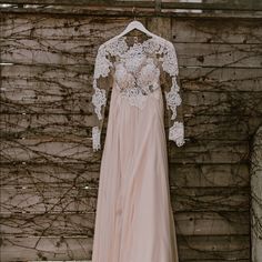 a wedding dress hanging on a wooden wall with vines in the background and a lace top