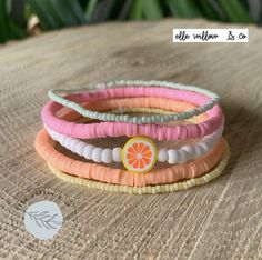 four different colored bracelets sitting on top of a wooden table next to a plant