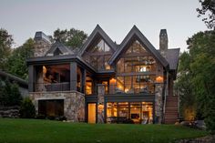 a large house sitting in the middle of a lush green field next to a forest