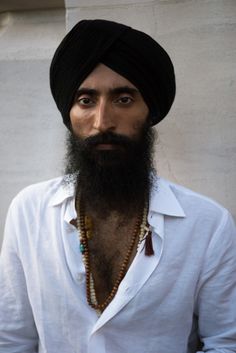 a man with a long beard wearing a turban and beaded necklaces