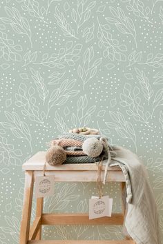 a teddy bear sitting on top of a wooden stool next to a wallpapered background