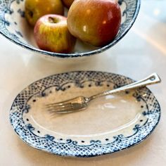 two plates with apples on them and a fork in the bowl next to each other