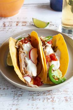 two tacos are sitting on a plate next to a drink