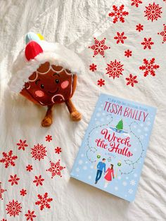 a book and stuffed animal laying on a bed with snowflakes in the background