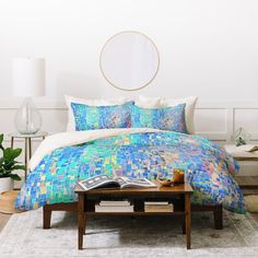 a bed with a blue comforter and pillows on top of it in a room