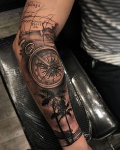 a man's arm with a compass and palm trees on the inside of it