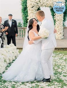 a bride and groom standing in front of a flowered arch at their wedding ceremony