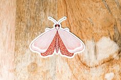 a close up of a sticker on a wooden surface with a butterfly shaped object in the middle