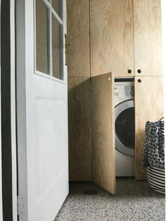 an open door to a washer and dryer in a room with wood paneling