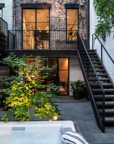 an outdoor hot tub in front of a brick building with stairs leading up to the second floor