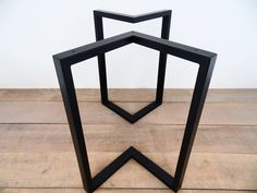 three black metal hexagons sitting on top of a wooden floor