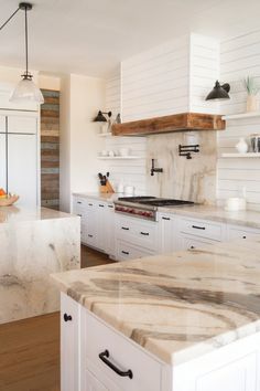 a kitchen with marble counter tops and white cabinets