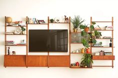 an entertainment center with bookshelves, shelves and a flat screen tv mounted on the wall