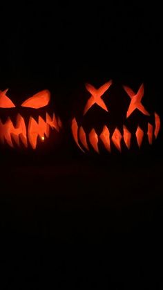 three carved pumpkins sitting in the dark