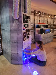 a woman kneeling down in front of a machine with blue lights on it's side