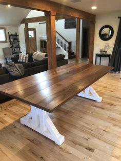 a wooden table sitting on top of a hard wood floor next to a living room