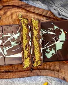 chocolate and pistachio bars on a wooden cutting board with two bananas in the background